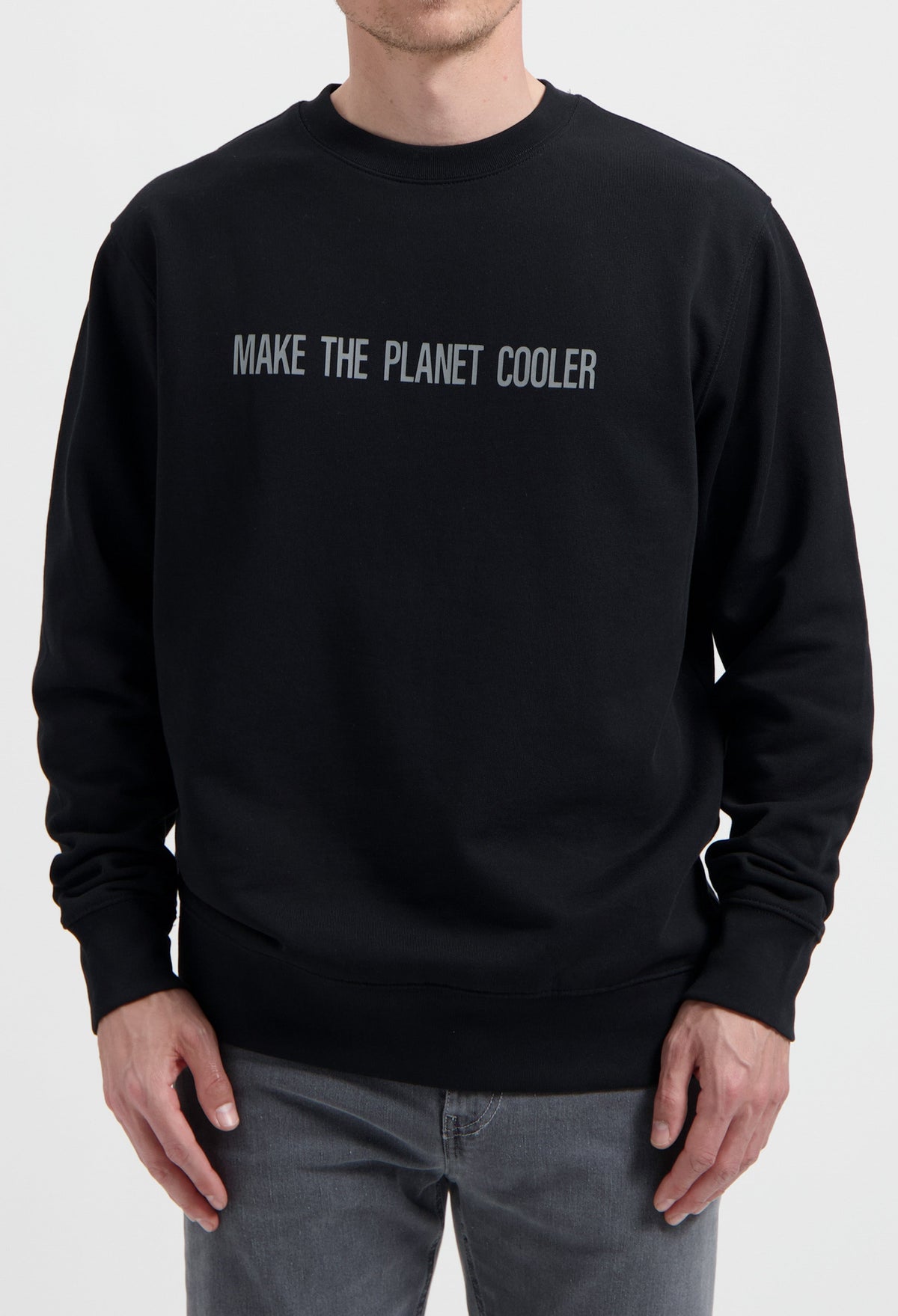 Sustainable MUD Jeans black sweater with "Make the Planet Cooler" slogan, paired with gray denim, ethical fashion choice.