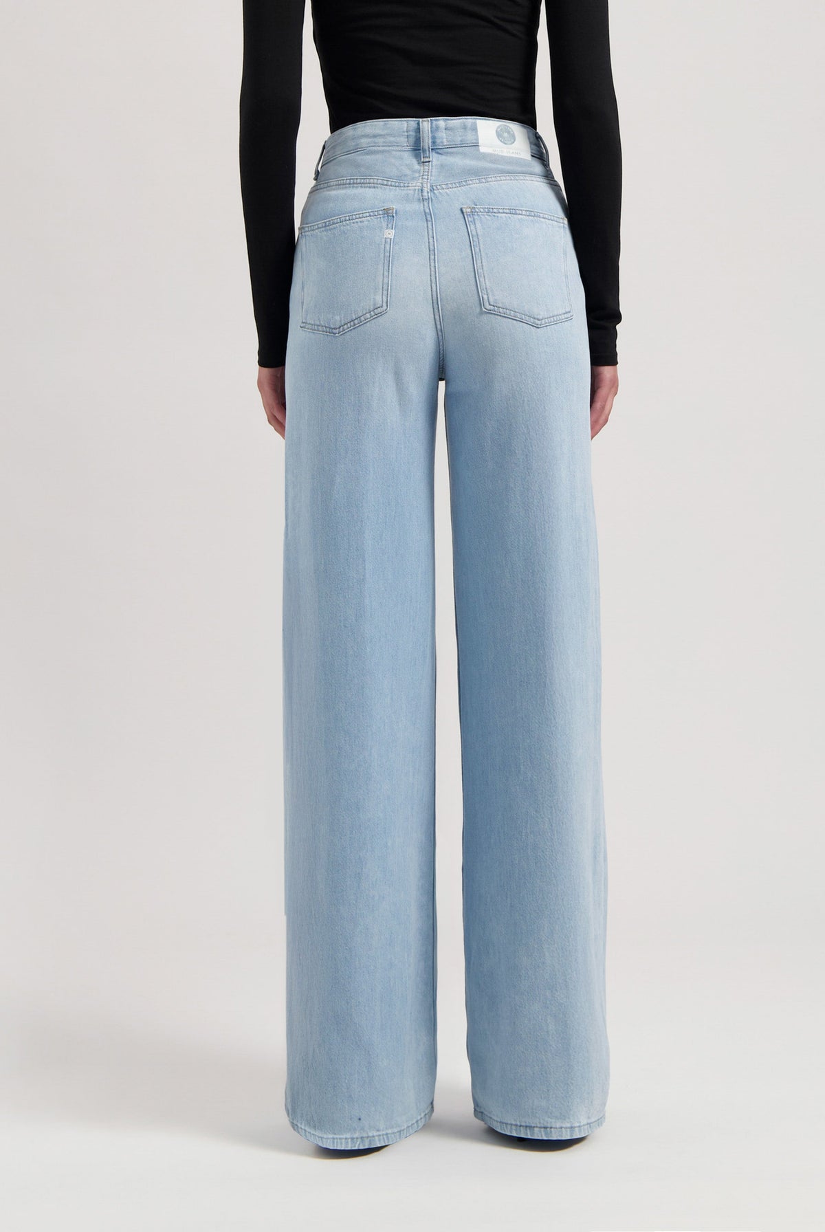 Light blue, wide-leg denim jeans made from organic cotton, shown worn with a black, long-sleeve top.