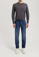 Sustainable MUD Jeans crafted from organic cotton, in a classic blue denim, paired with a gray sweater and white sneakers.