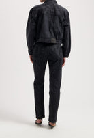 Black denim jacket and jeans set from MUD Jeans, featuring a textured finish, worn with strappy black sandals.
