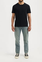 Sustainable MUD Jeans dark blue denim jacket made from organic materials, worn over a white shirt and blue jeans.