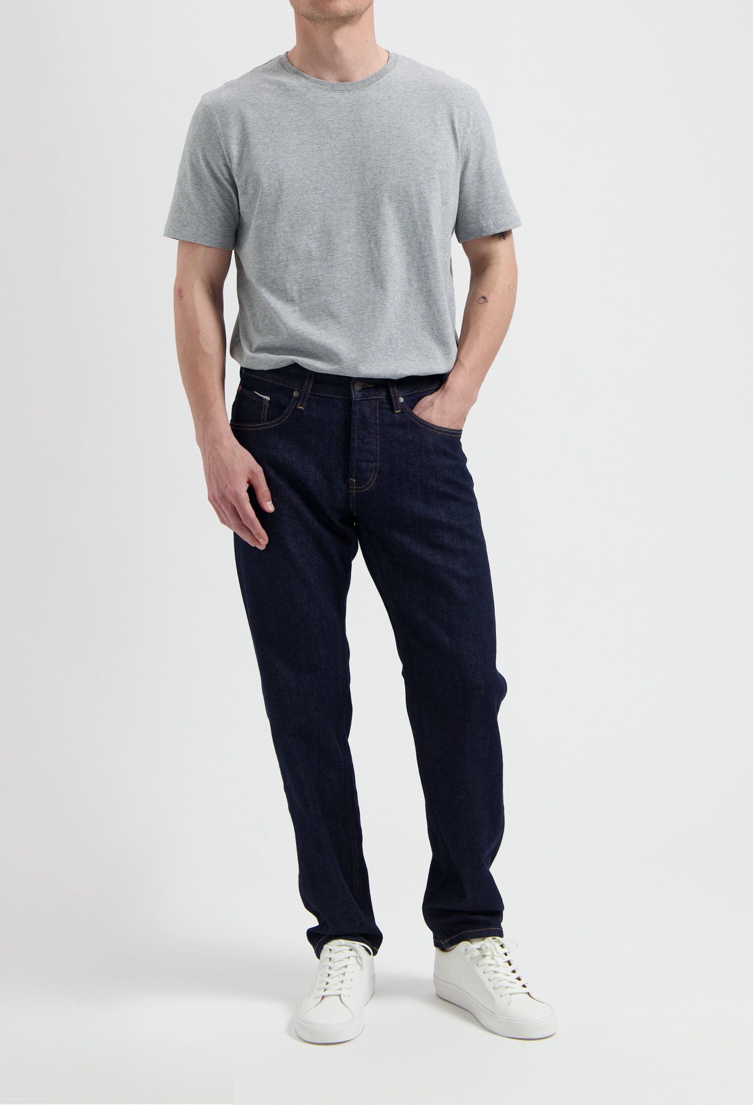 Sustainable MUD Jeans in blue denim, classic fit, paired with a gray t-shirt featuring eco-friendly messaging.