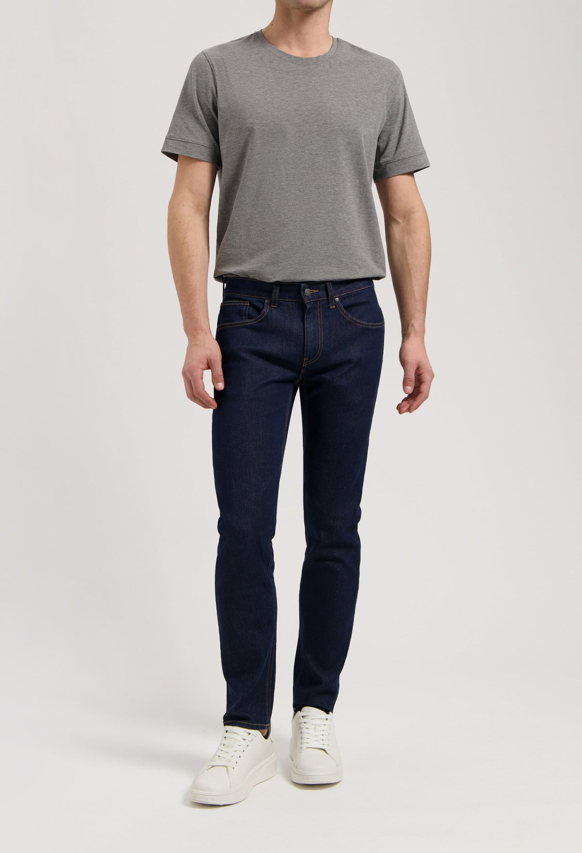 Sustainable MUD Jeans in a dark wash, crafted from organic materials, paired with a stylish gray sweater.