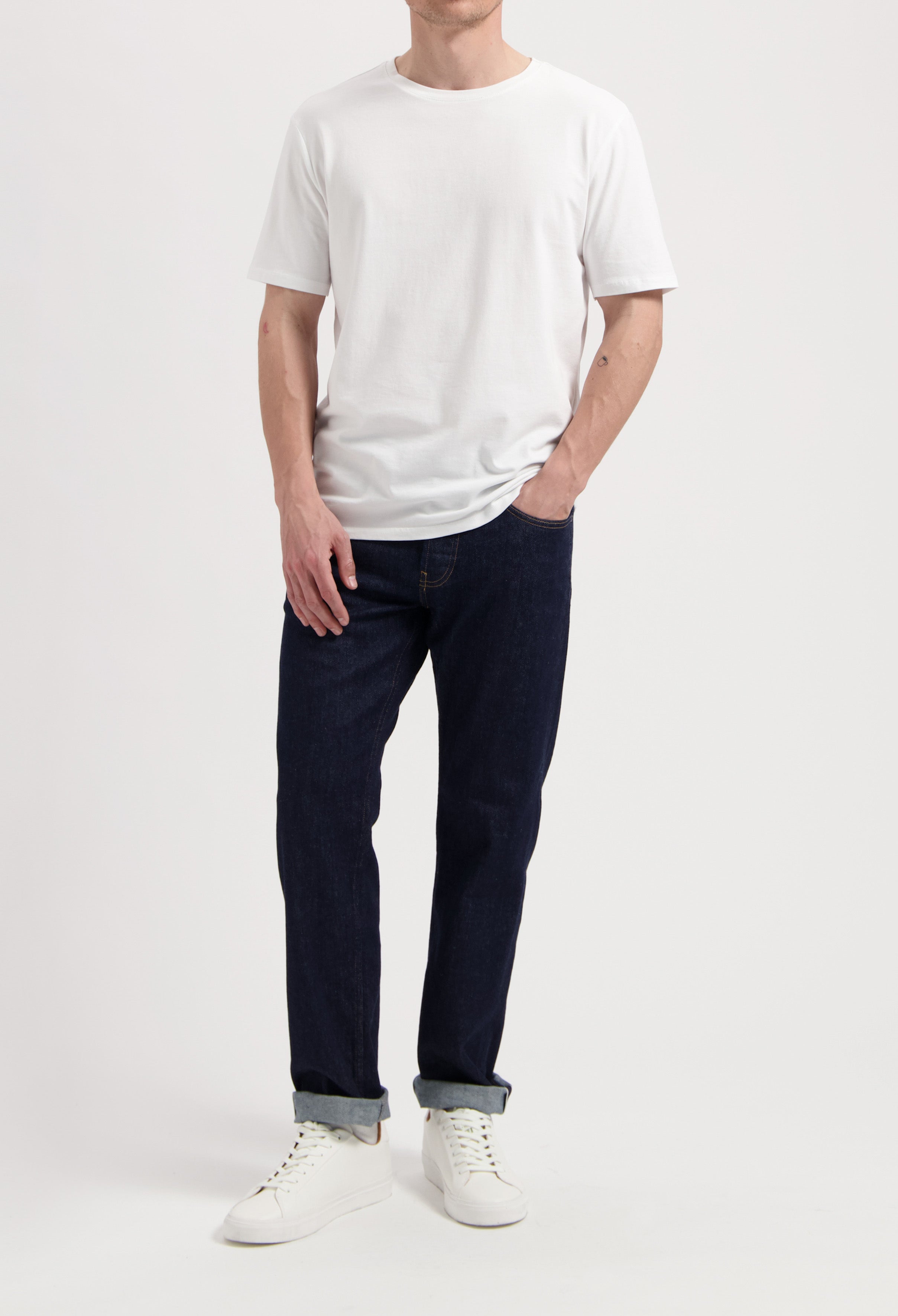 Sustainable MUD Jeans ensemble with dark denim jacket, light blue jeans, and white sneakers, embodying ethical fashion.