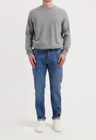 Sustainable MUD Jeans in deep blue denim, crafted from organic cotton, paired elegantly with a soft gray sweater.