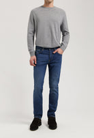 Sustainable MUD Jeans in dark blue denim, crafted from organic cotton, styled with a classic gray sweater for an ethical look.