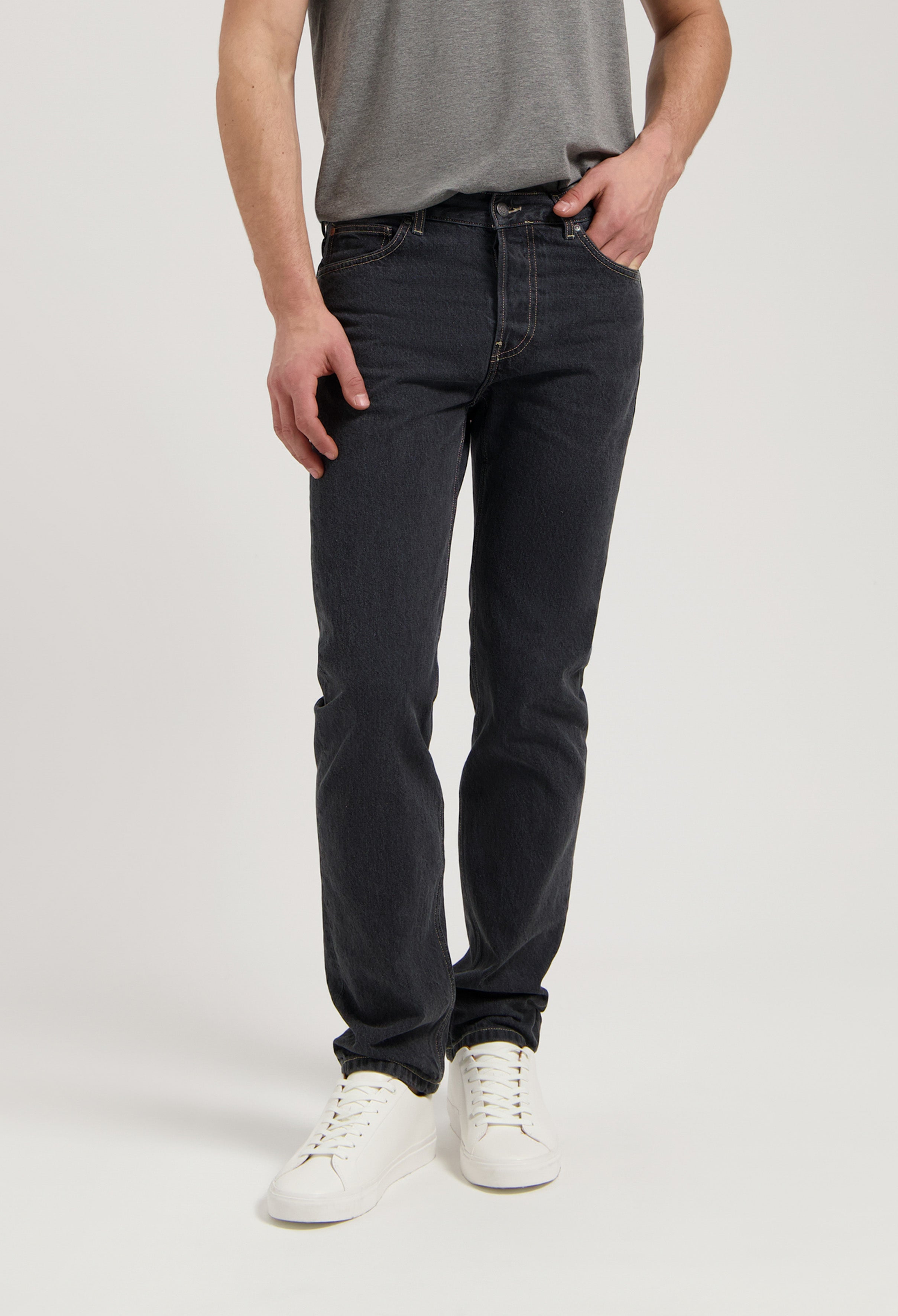 Sustainable MUD Jeans in dark denim, ethically made with organic cotton, paired with black loafers and white ribbed sweater.