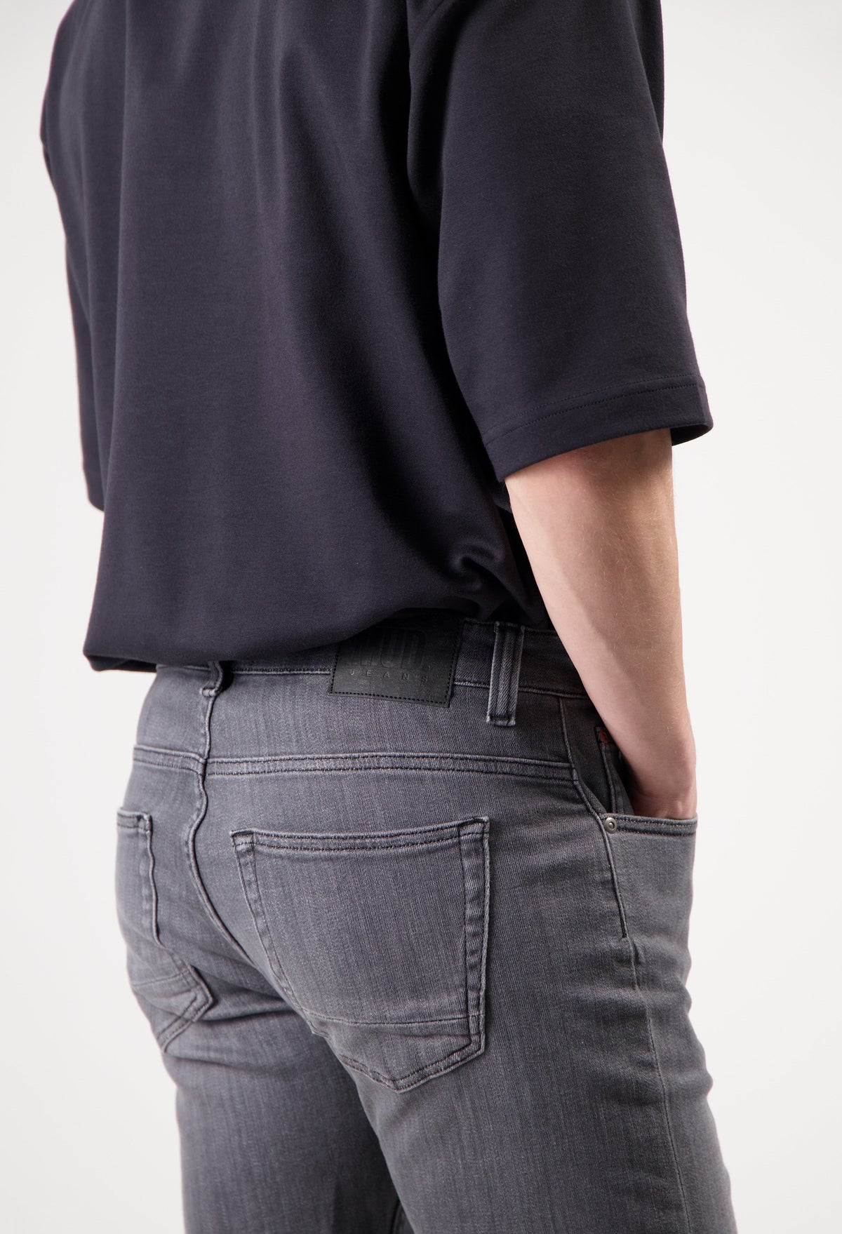 Sustainable MUD Jeans in dark blue denim, crafted ethically, paired with a casual gray T-shirt and white sneakers.