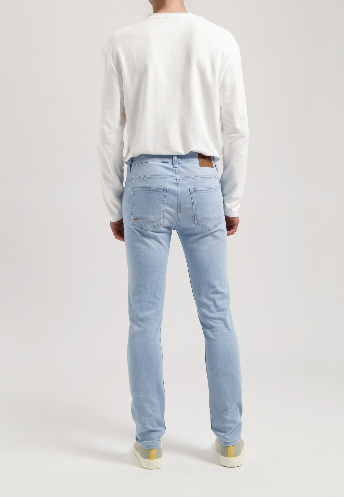 Sustainable MUD Jeans in dark denim, paired with a soft gray sweater, showcasing ethical and stylish fashion.