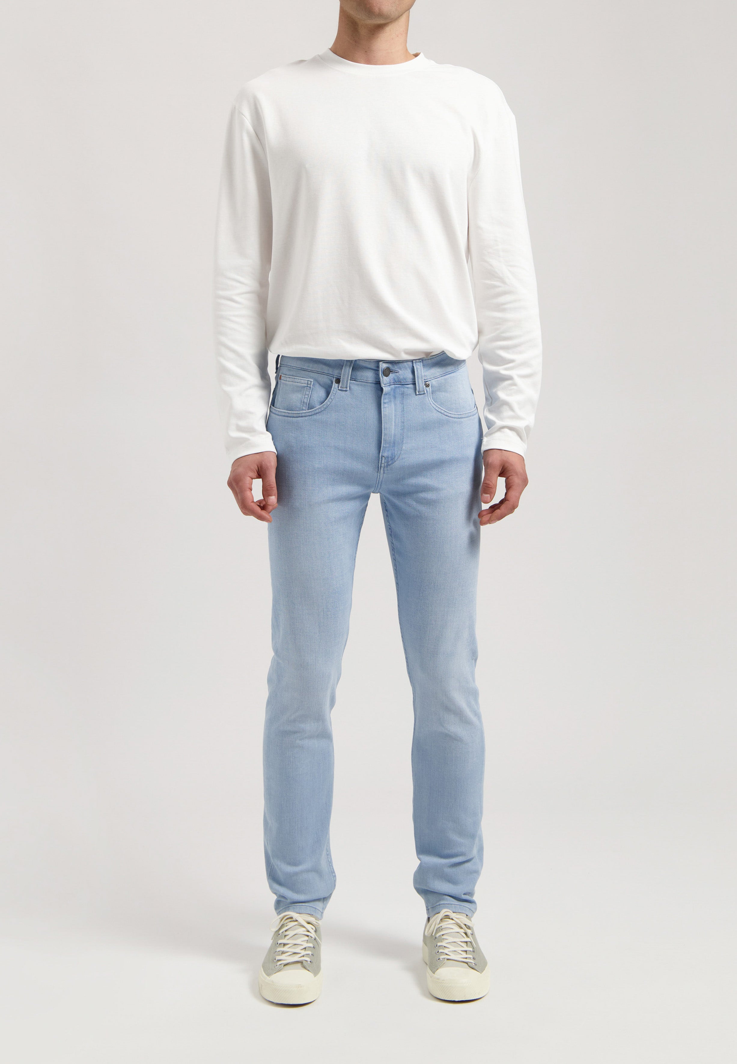 Sustainable MUD Jeans in classic blue denim, paired with a black jacket and white tee, styled for an ethical urban look.