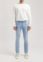 Sustainable MUD Jeans in classic blue denim, paired with a black jacket and white tee, styled for an ethical urban look.