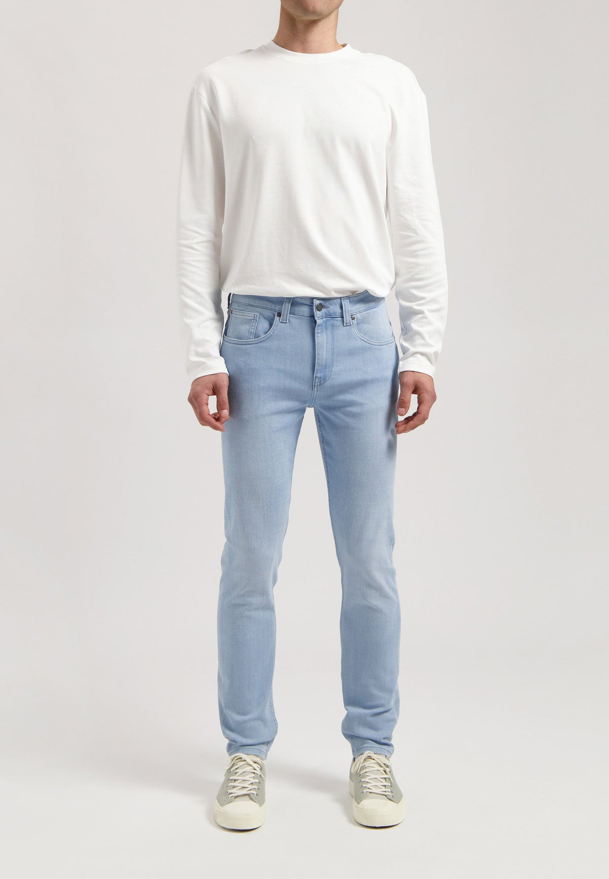 Sustainable MUD Jeans in classic blue denim, paired with a black jacket and white tee, styled for an ethical urban look.