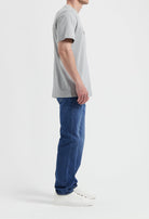 Sustainable MUD Jeans featuring beige denim, crafted ethically, paired with a casual gray t-shirt and sneakers.