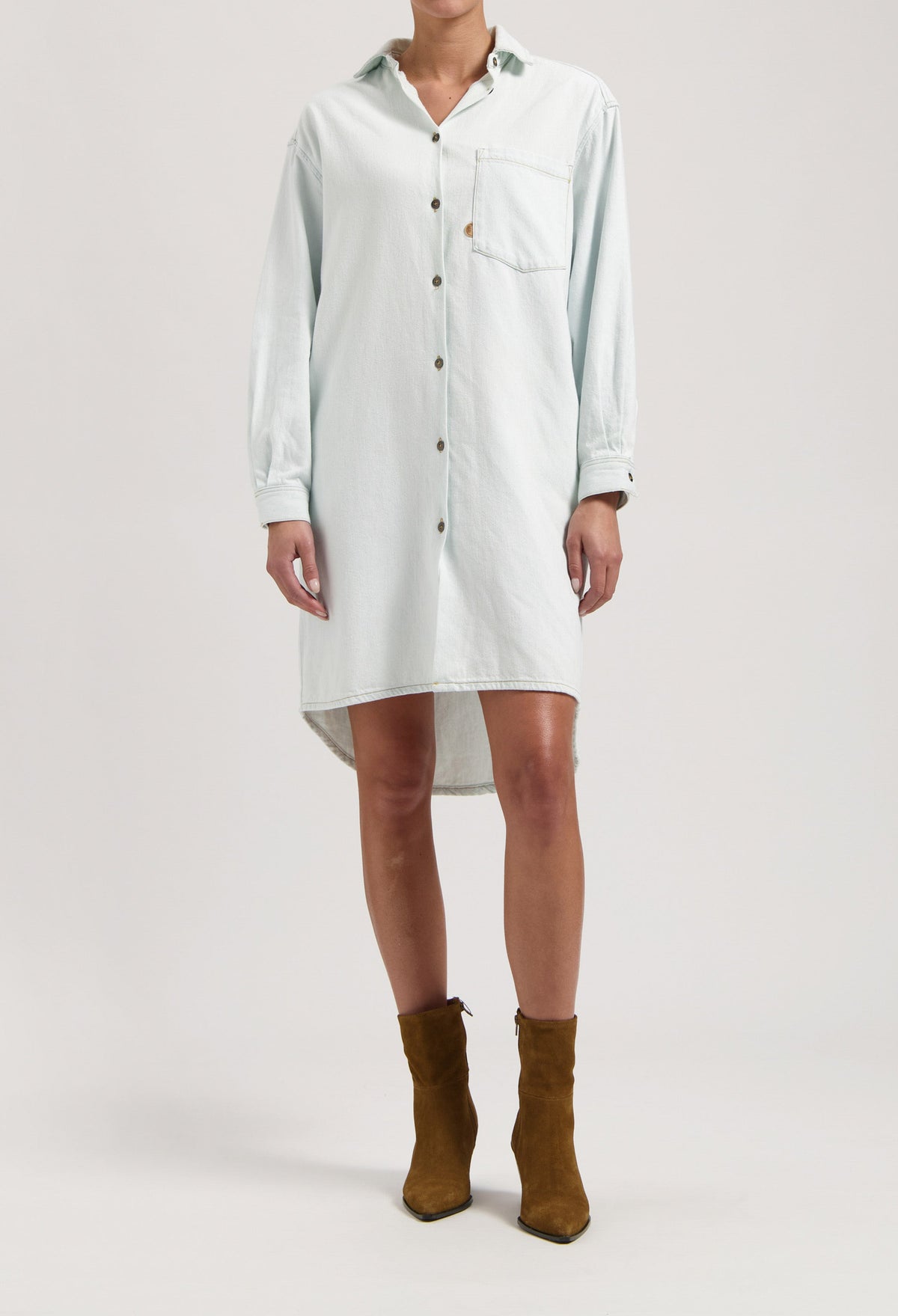 Light blue button-up denim shirt dress with long sleeves, worn with brown suede ankle boots.