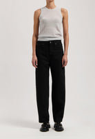 Model wearing a light gray sleeveless top and high-waisted black wide-leg jeans, paired with black shoes, against a plain background.