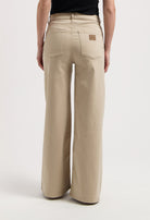 Wide-leg stone-colored MUD Jeans made from organic cotton, showcasing high-waisted fit and detailed back pockets.