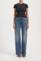Wide-leg blue jeans with faded effect, paired with a fitted black short-sleeve top, worn by a model against a plain background.