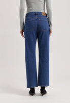 Back view of sustainable MUD Jeans, organic blue denim, wide-leg fit, paired with a light gray long-sleeve top.