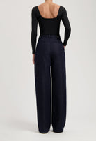 High-waisted wide-leg jeans in dark indigo denim, paired with a sleek black long-sleeve bodysuit featuring an open back.