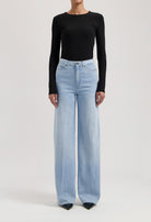 Wide-leg light blue jeans paired with a sleek black long-sleeve top, showcasing modern casual fashion.