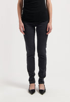 Chic black slim-fit pants paired with a sleeveless top and pointed black heels on white background, highlighting stylish casual wear.