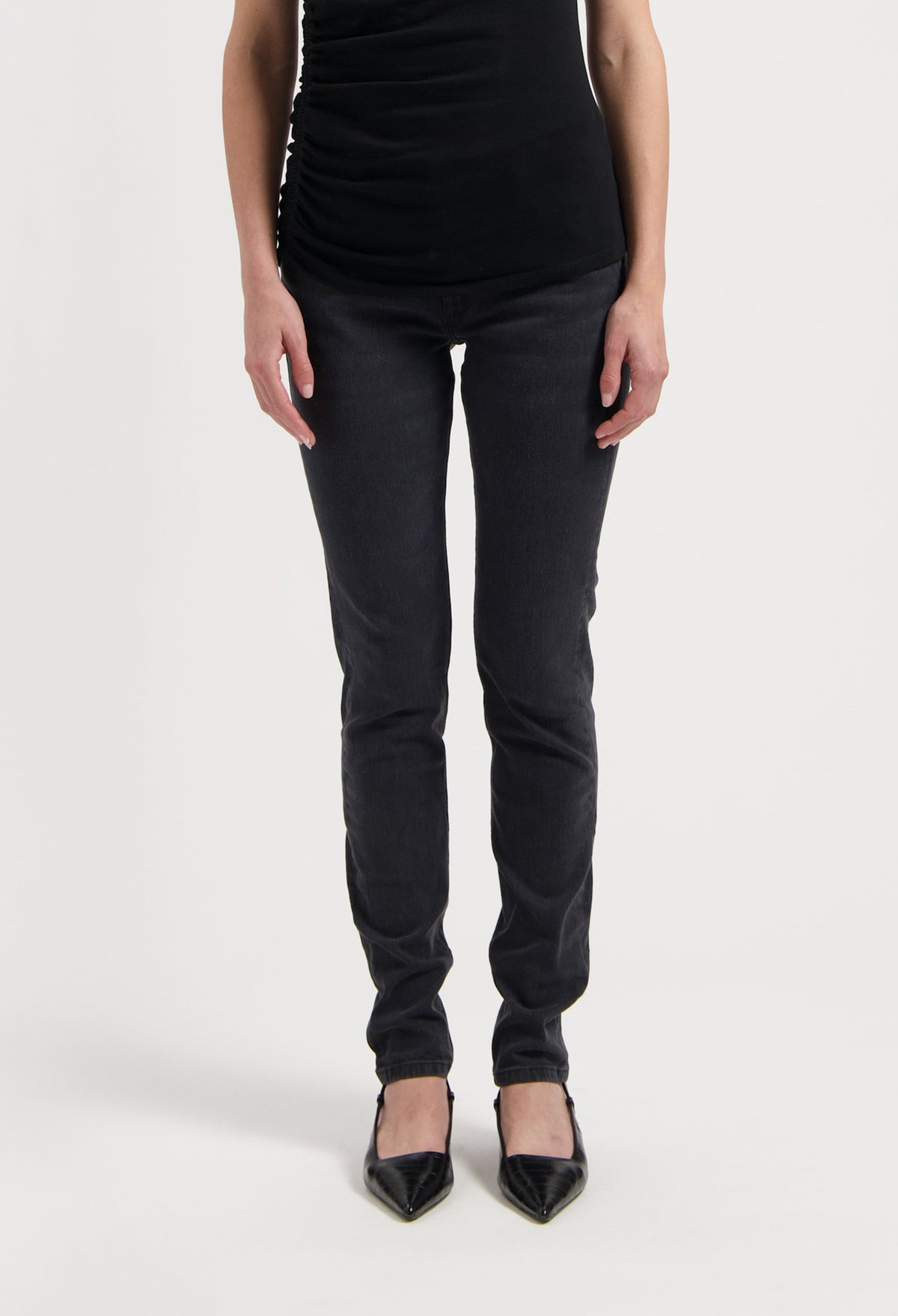 Chic black slim-fit pants paired with a sleeveless top and pointed black heels on white background, highlighting stylish casual wear.
