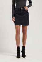 Woman wearing a black denim skirt paired with a fitted gray long-sleeve top and black ankle boots.