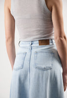 Light blue denim MUD Jeans skirt with high waist and back pockets, paired with a sleeveless light gray top.